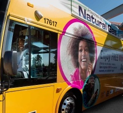 photo of a LVCCLD Executive Director Kelvin Watson behind the wheel of a Regional Transportation Commission of Southern Nevada bus with an ad on the side of the bus promoting the library