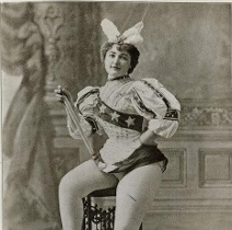 Archival image of a burlesque dancer sitting on a chair