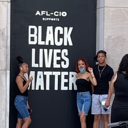 Activists stand near a Black Lives Matter Labor Union Banner